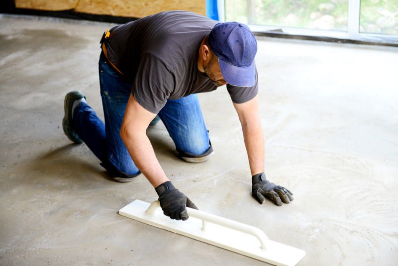 worker finishing concrete floor with a trowel