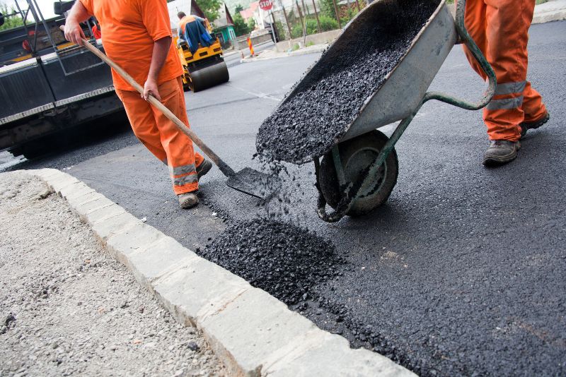 two workers installing asphalt paving